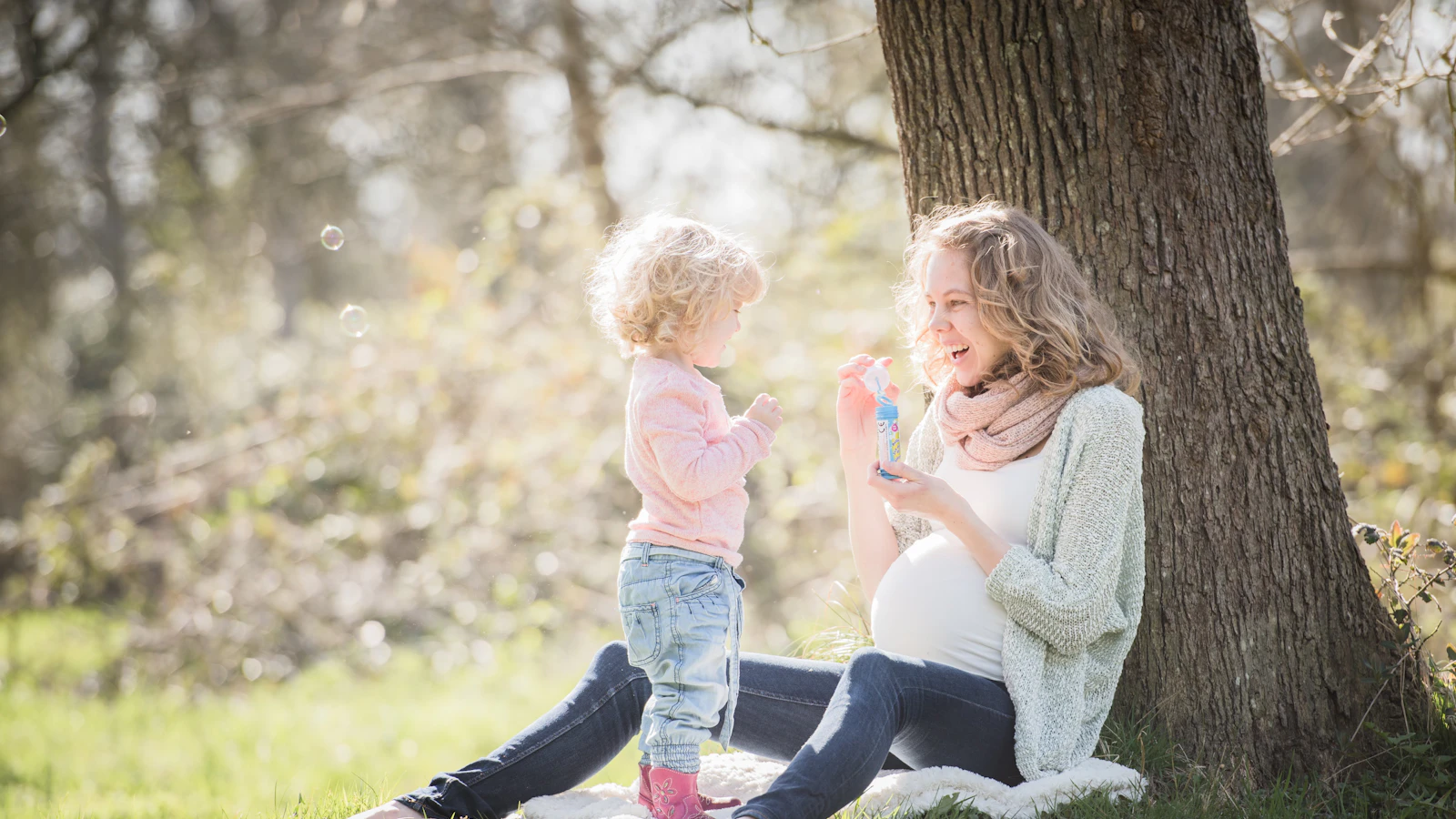 A pregnant woman sitting outdoors with a young child