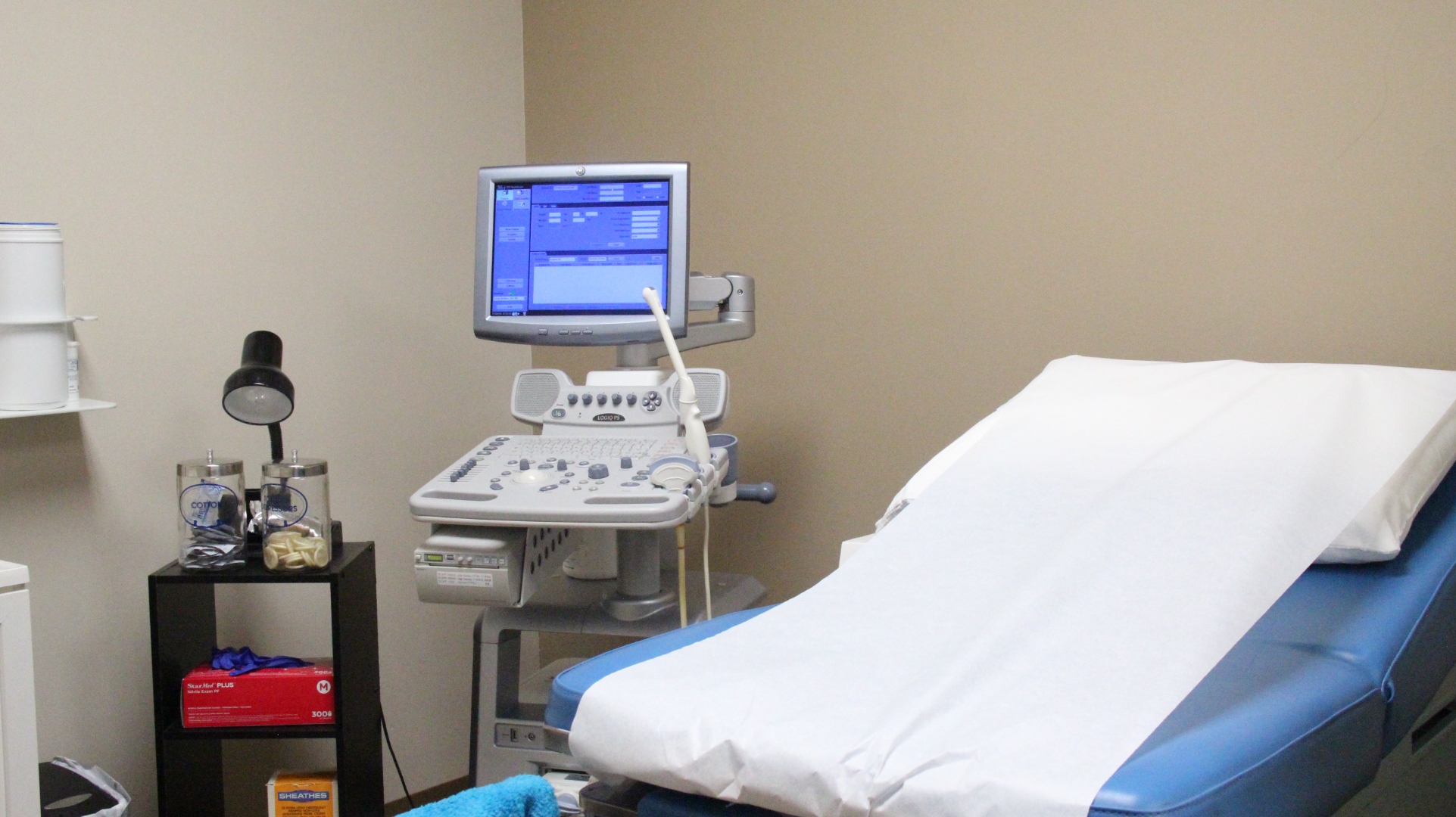 A clean medical exam room with an ultrasound machine and patient chair.