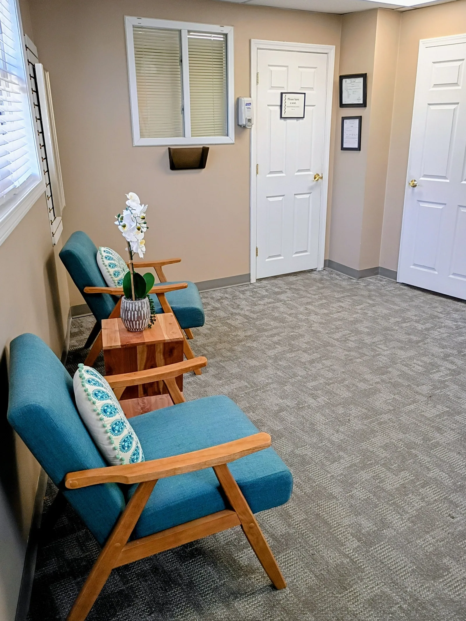 The welcoming entry and waiting area at our Revere clinic, with teal chairs, fresh orchids, and a quiet, calm atmosphere.